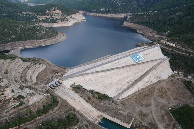 Aerial view of Tahtalı Dam, its concrete face marked DSİ, holding back a reservoir in wooded hills.